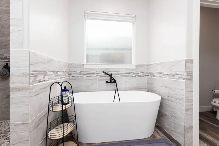 Bathroom featuring tile walls, a freestanding bath, wainscoting, and wood finished floors