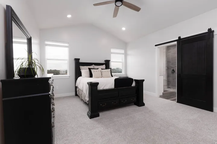Bedroom featuring a barn door, light colored carpet, vaulted ceiling, recessed lighting, and ceiling fan
