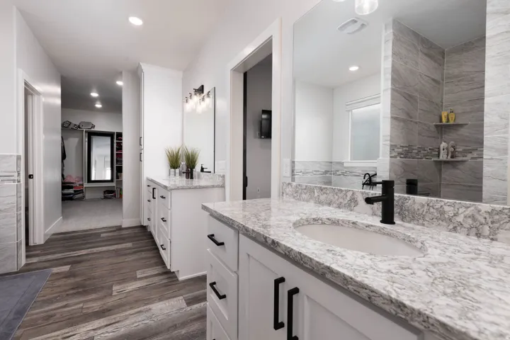 Full bathroom with two vanities, dark wood finished floors, and recessed lighting