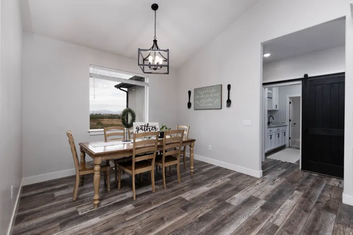 Dining space featuring lofted ceiling, a barn door, dark wood-type flooring, and suspended lighting