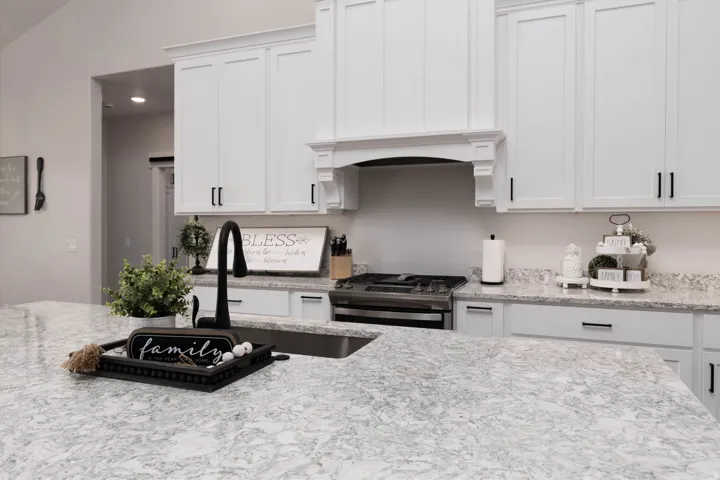Kitchen featuring white cabinetry, gas range, and light stone countertops