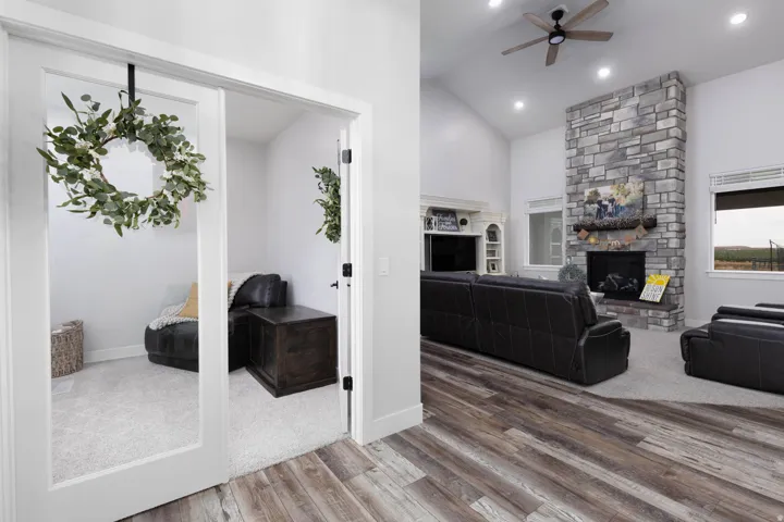 Living area with a fireplace, ceiling fan, vaulted ceiling, and wood finished floors