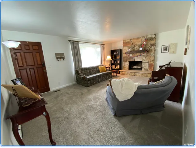 Living room featuring carpet and a stone fireplace