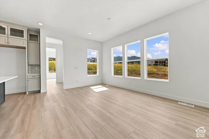 Open-concept area with wood-finish flooring, recessed lighting, and custom cabinetry featuring glass-front upper doors and a chevron-pattern backsplash