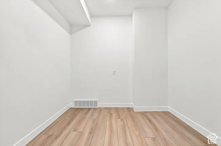 Neutral interior space featuring wood-finish flooring, crisp white walls, and a recessed ceiling design