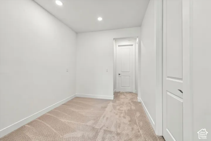 Neutral interior space featuring high-pile wall-to-wall carpeting, recessed LED lighting, and two-panel interior doors