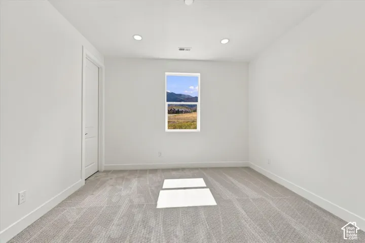 Room featuring neutral-toned carpeting, recessed ceiling lighting, and a window with mountain scenery