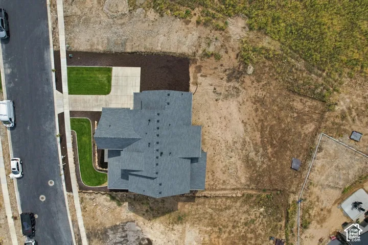 Aerial perspective of a property featuring an asphalt driveway, concrete walkway, and asphalt shingle roof