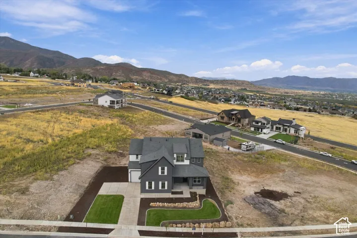 Two-story residence with dark-toned horizontal siding, contrasting white trim, covered entryway, and mountain backdrop