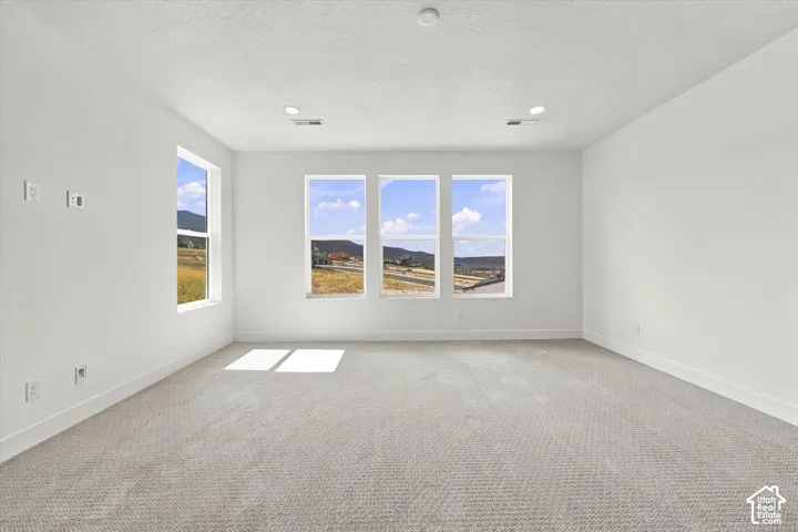 Expansive room featuring wall-to-wall carpeting, neutral paint, recessed lighting, and multiple windows with mountain scenery