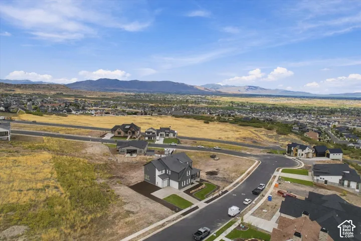 Aerial perspective featuring a residential lot with mountain backdrops and paved street infrastructure