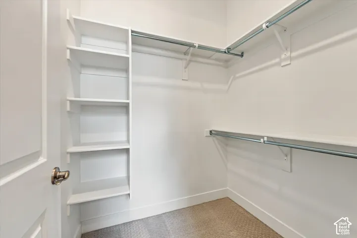 Walk-in closet featuring white built-in shelving and dual-tier metal hanging rods
