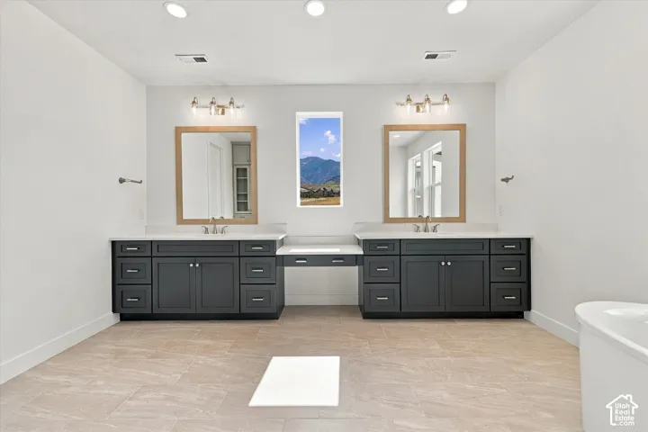 Dual dark-finish cabinetry featuring white countertops, recessed lighting, integrated mirrors with wood-toned frames, and ceramic tile flooring
