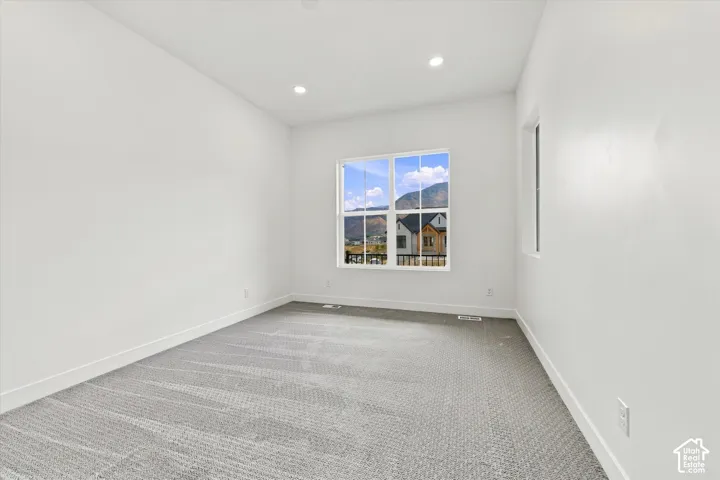 Neutral-toned carpeting, recessed ceiling lighting, and expansive windows featuring mountain scenery