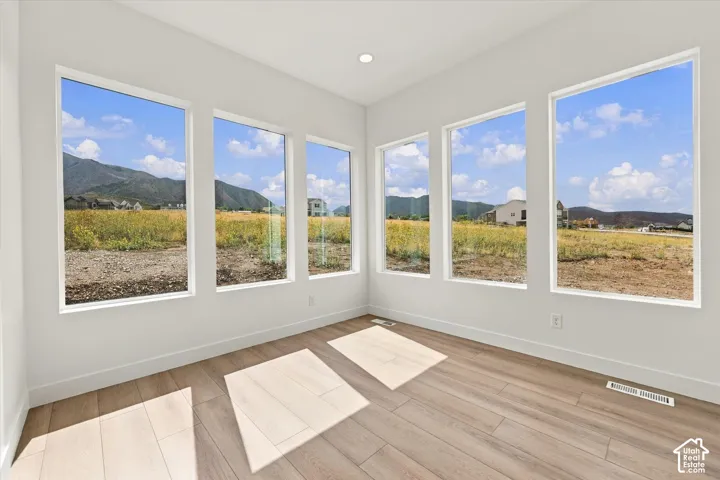 Neutral wall finishes, wood-finish flooring, recessed lighting, and multiple oversized windows showcasing mountain scenery