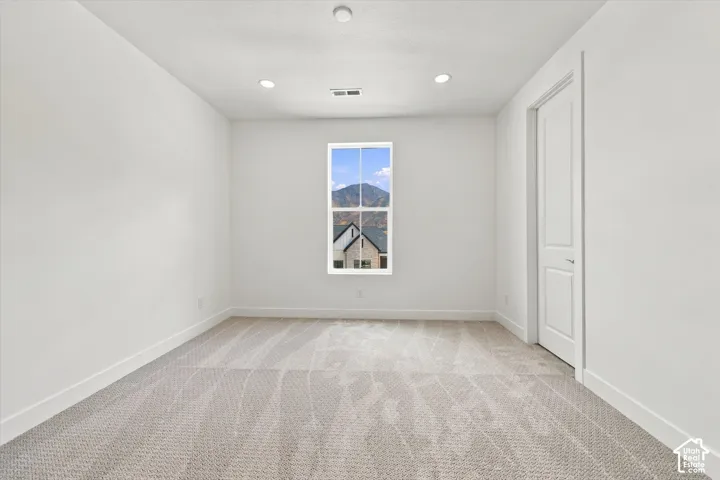 Neutral interior space featuring high-pile carpet, recessed lighting, a single-panel interior door, and a centered window with mountain scenery