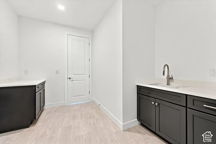 Dark cabinetry with neutral countertops, recessed lighting, tile flooring, and a stainless steel high-arc faucet