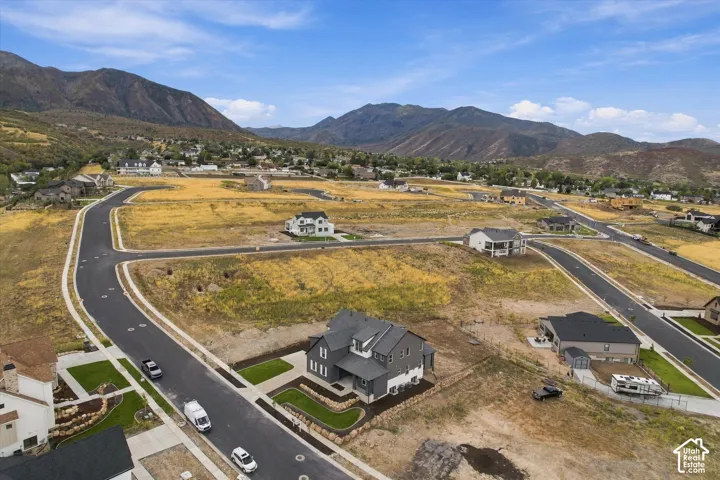 Aerial view of a residential development featuring newly constructed homes, paved roads, and a prominent mountain range backdrop