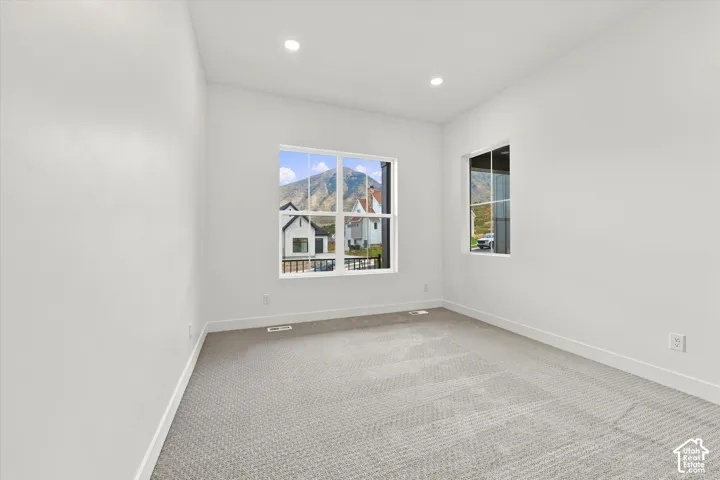 Neutral-toned carpeting, recessed ceiling lighting, and large windows with mountain scenery
