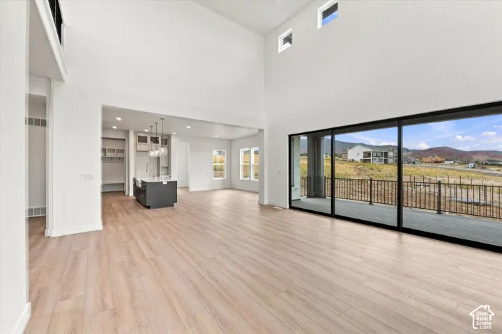 Double-height ceilings featuring transom windows, wood-finish flooring, floor-to-ceiling sliding glass doors, and a kitchen island with pendant lighting