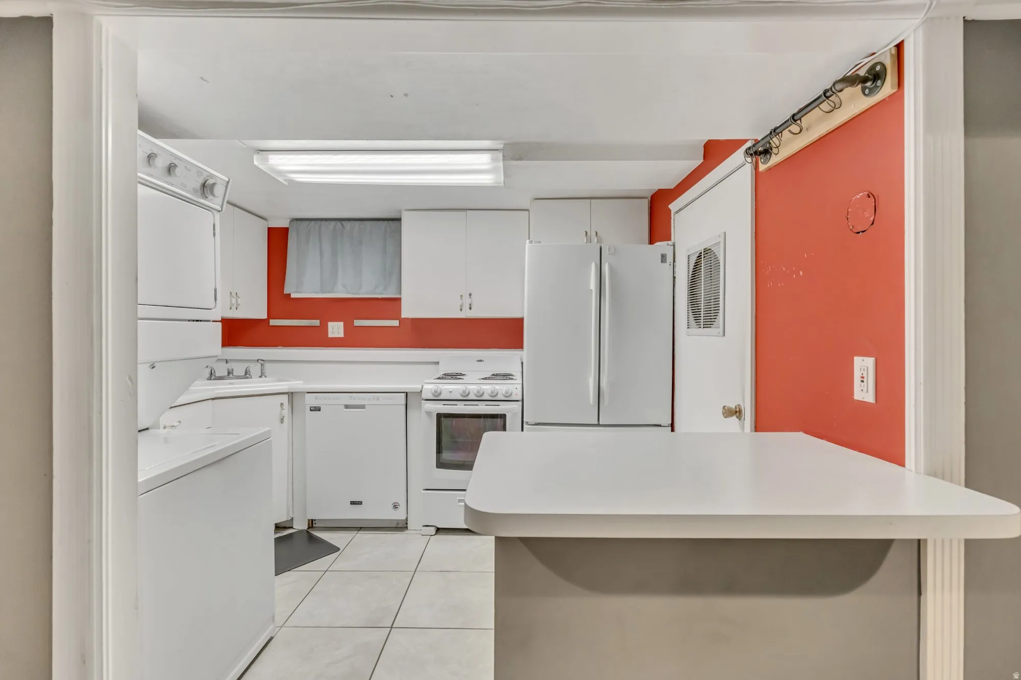 Kitchen with white appliances, white cabinets, light countertops, and light tile patterned floors