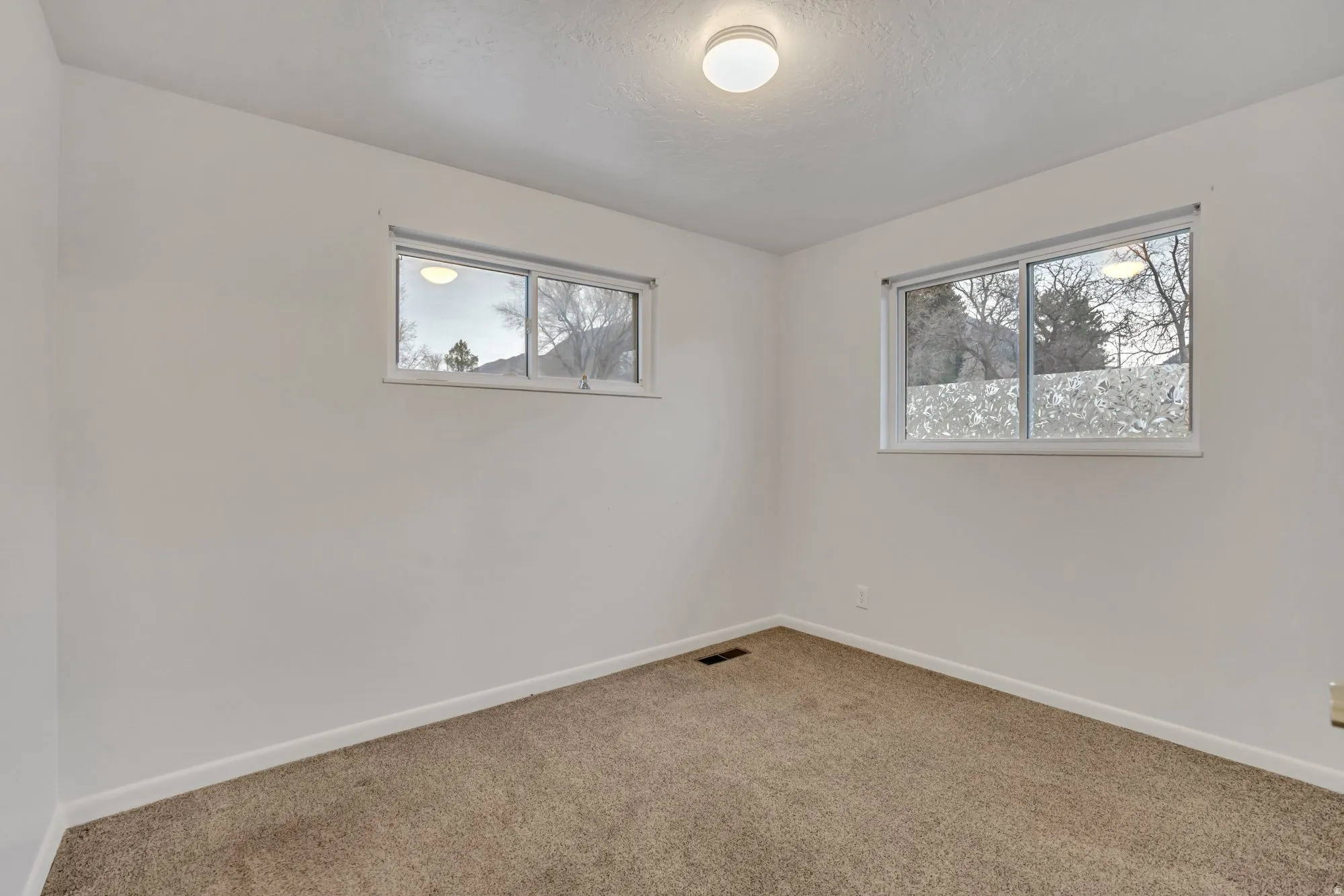 Bright bedroom with dual windows providing balanced natural light and functional layout options.