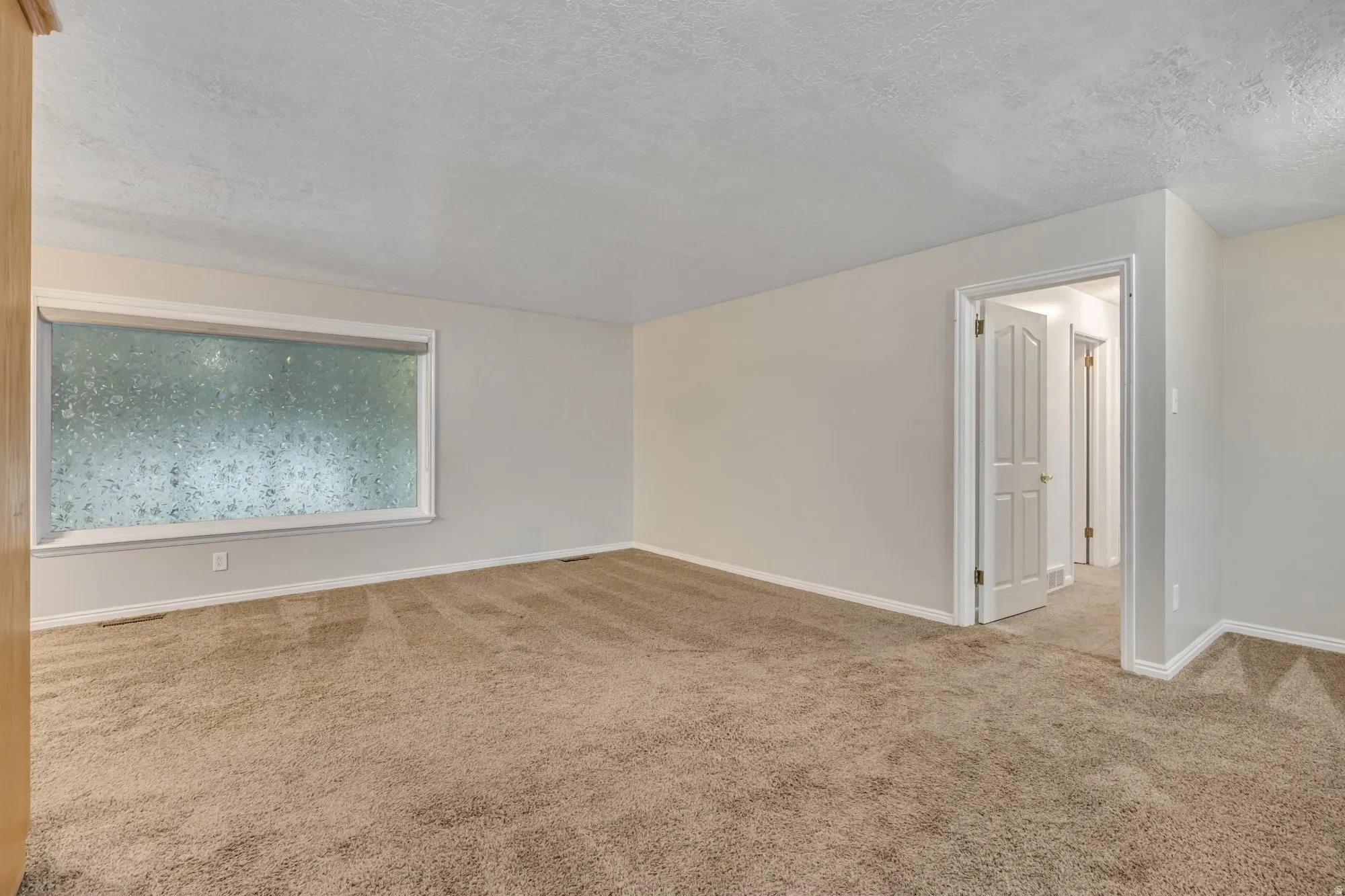 Spacious bedroom with extended wall space and natural light, ideal for primary suite setup or flexible living arrangement.