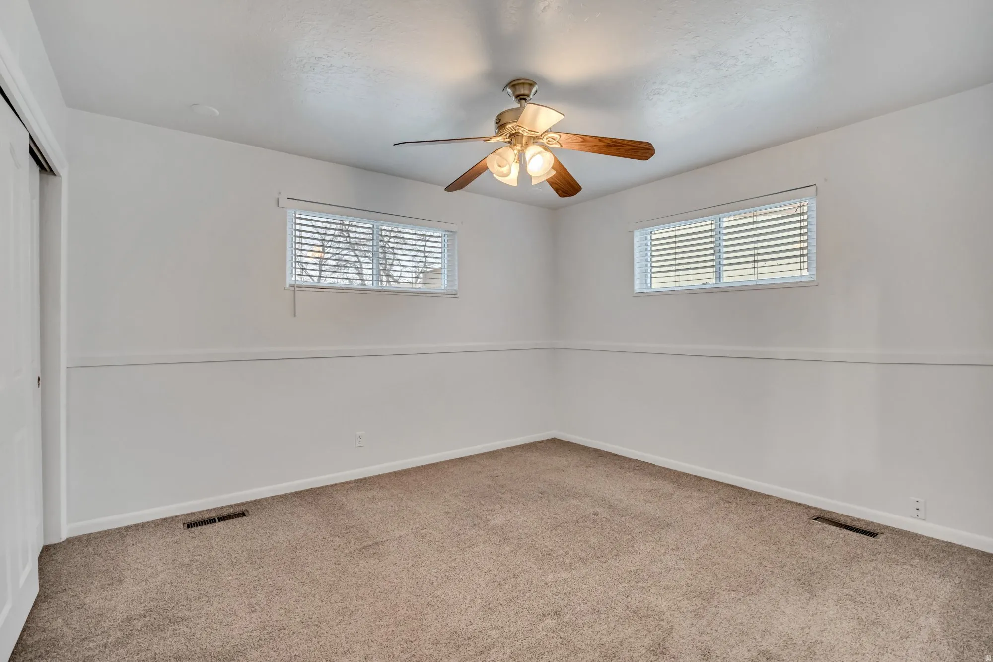 Well-sized bedroom with ceiling fan and multiple windows, providing natural light and comfortable living space.