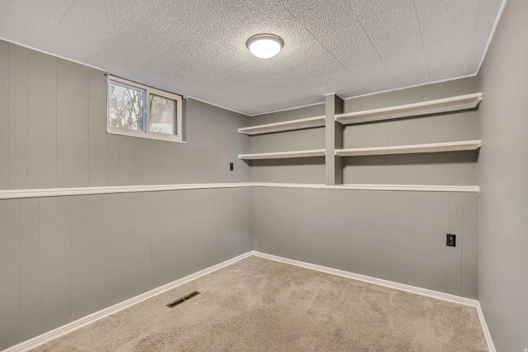 Lower-level bedroom with built-in shelving and flexible layout, ideal for guest space, rental setup, or home office configuration.