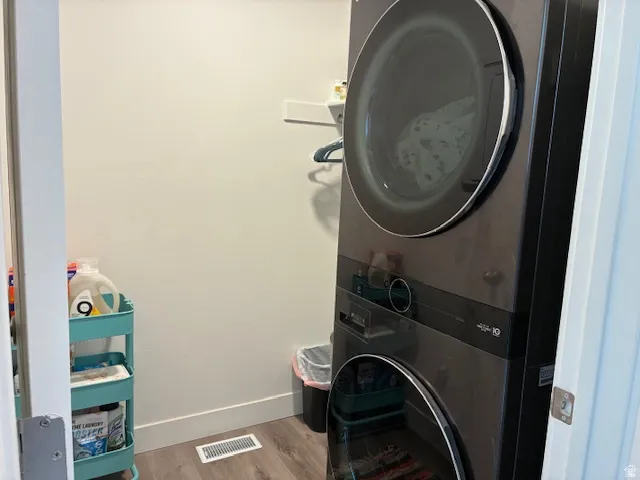 Laundry area featuring light wood finished floors and stacked washer / drying machine