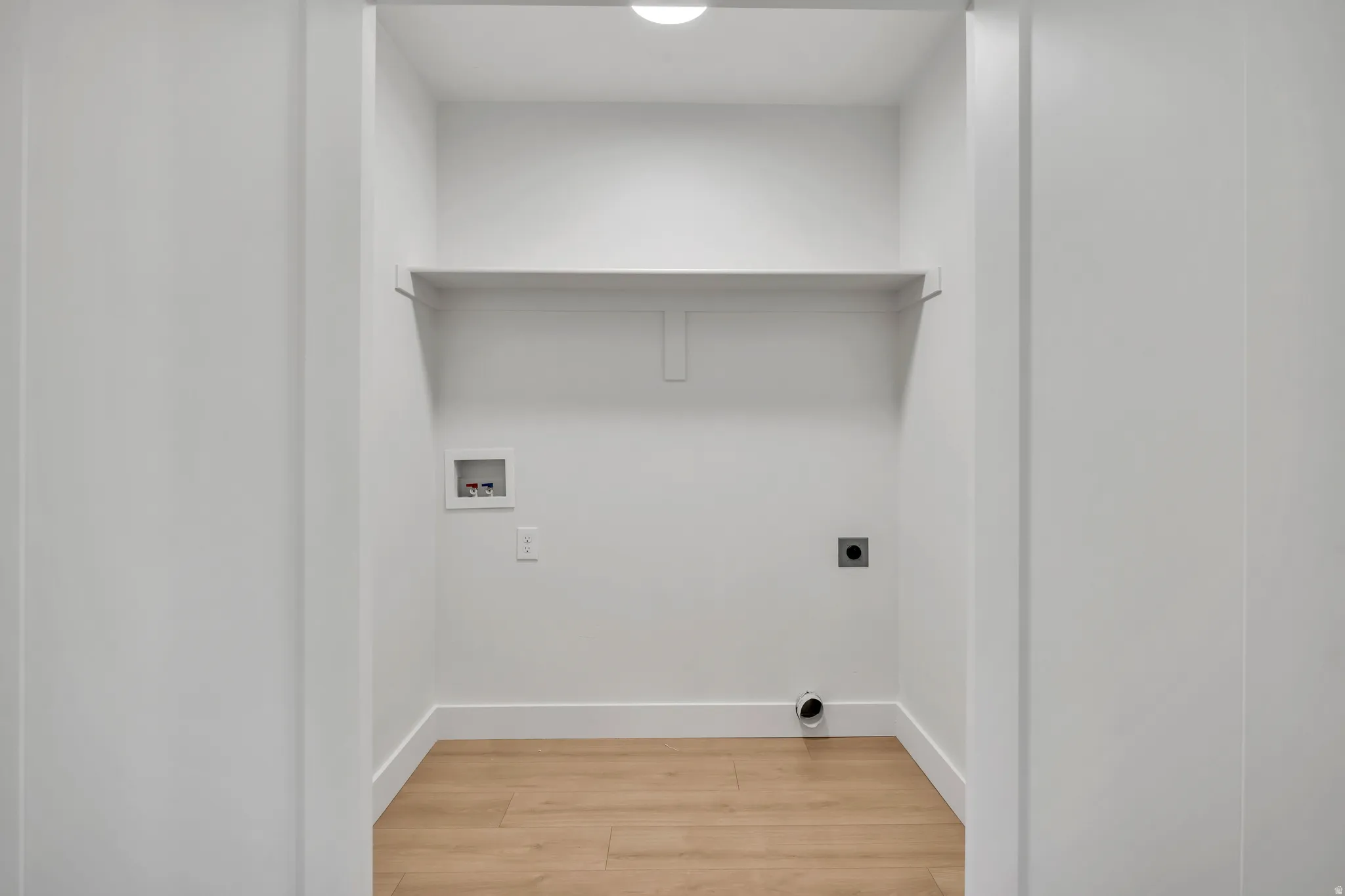 Laundry area featuring light wood-type flooring, hookup for an electric dryer, and washer hookup
