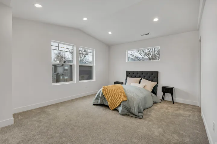 Carpeted bedroom featuring recessed lighting, lofted ceiling, and multiple windows
