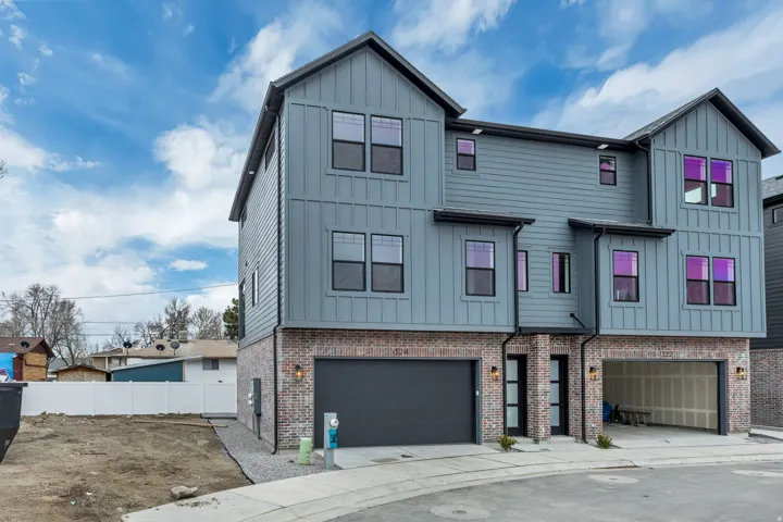 View of front of property with board and batten siding, an attached garage, and brick siding