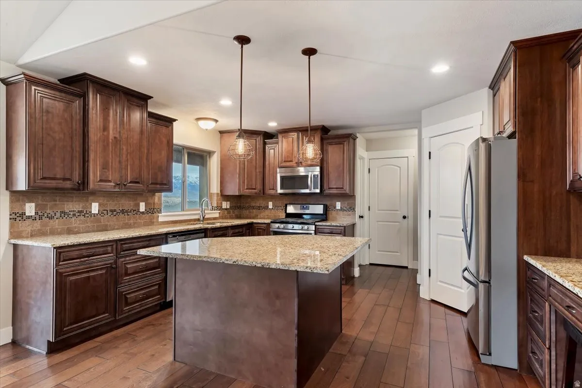 Kitchen featuring stainless steel appliances, dark wood finish cabinets, pendant lighting, and dark wood-type flooring