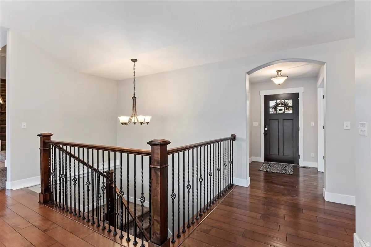 Entryway with arched walkways, dark wood-type flooring, and hanging lights
