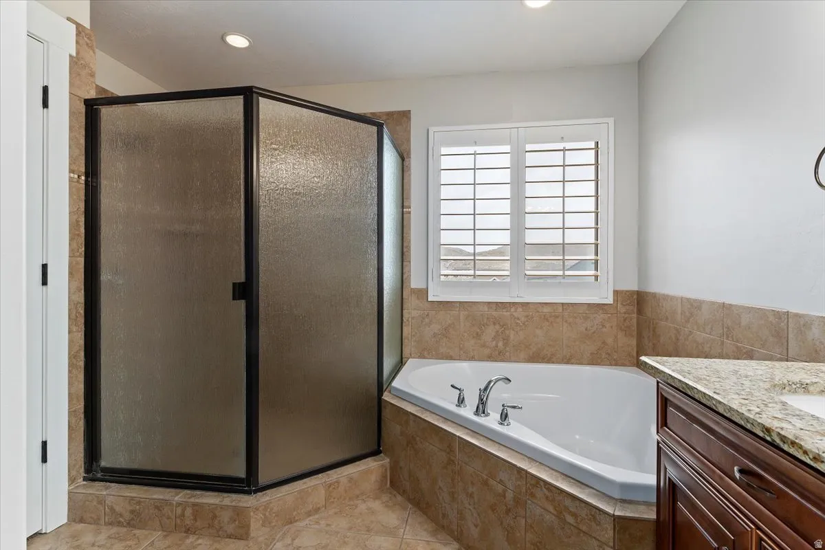 Bathroom featuring vanity, a shower stall, a garden tub, recessed lighting, and light tile patterned floors