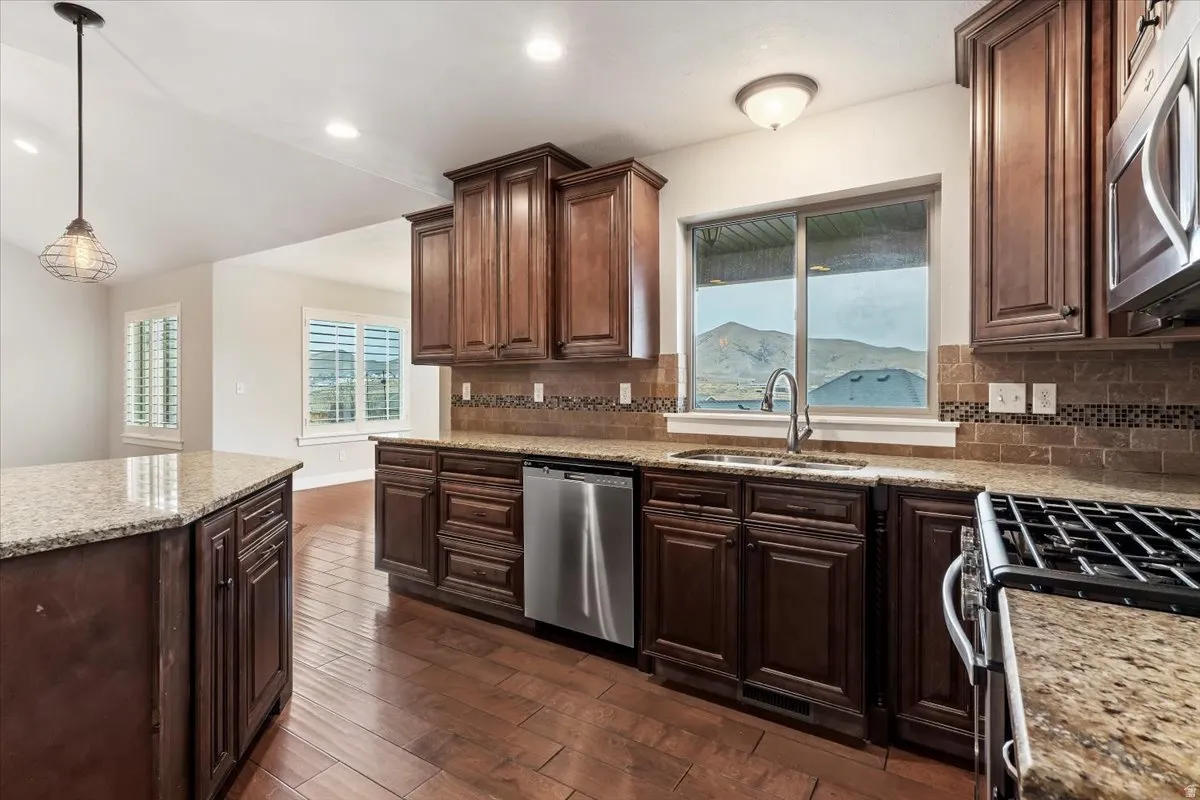Kitchen with dark wood-type flooring, dark wood finish cabinetry, stainless steel appliances, and plenty of natural light