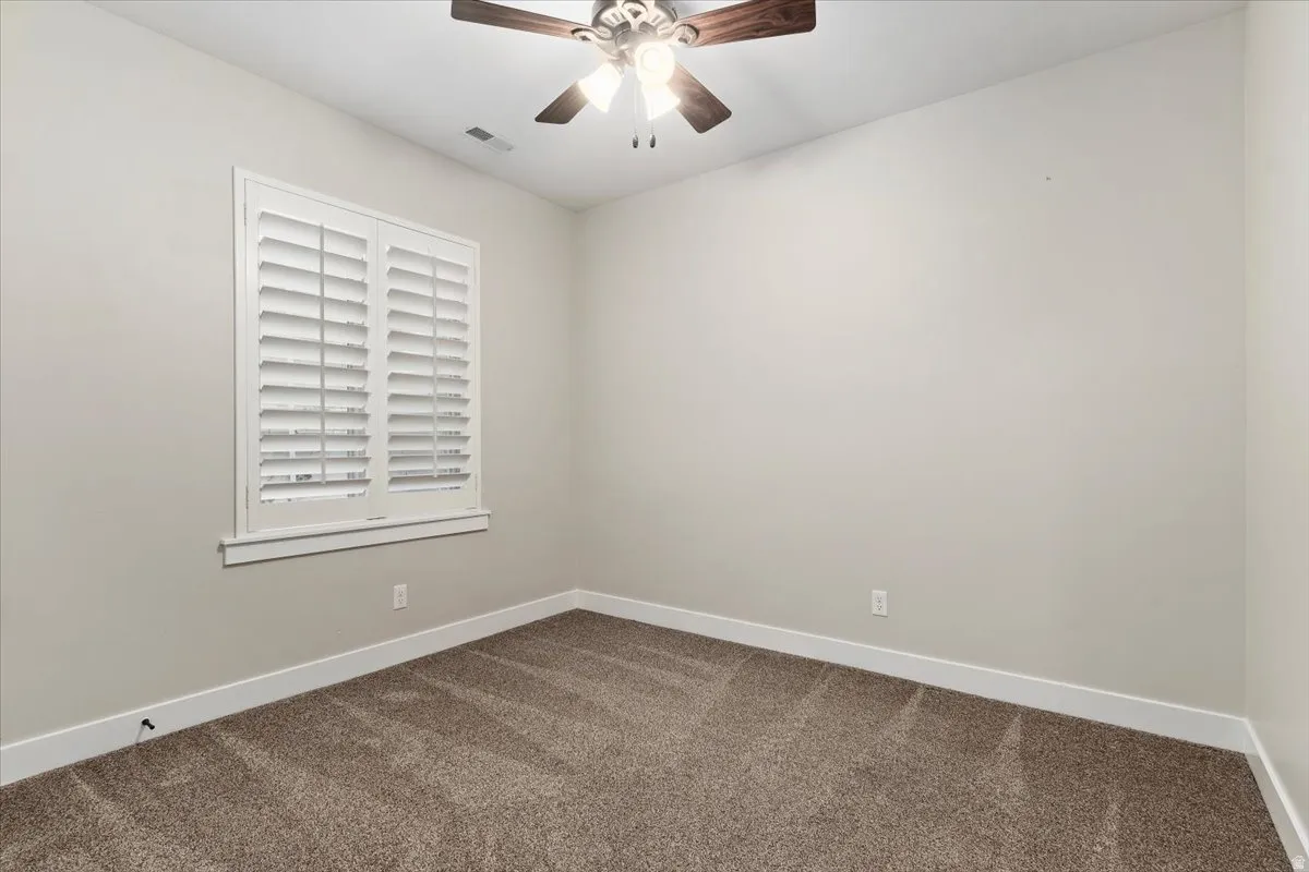 Unfurnished room featuring carpet floors and ceiling fan