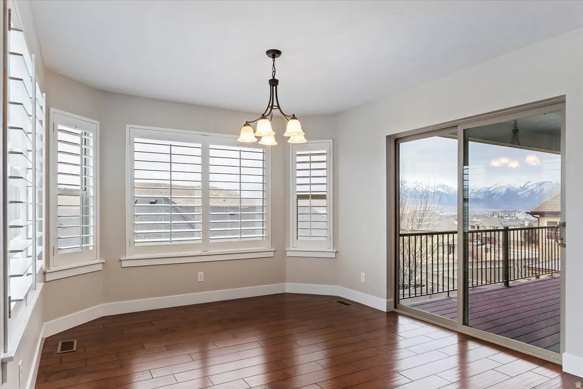 Spare room with hanging lights and dark wood-type flooring