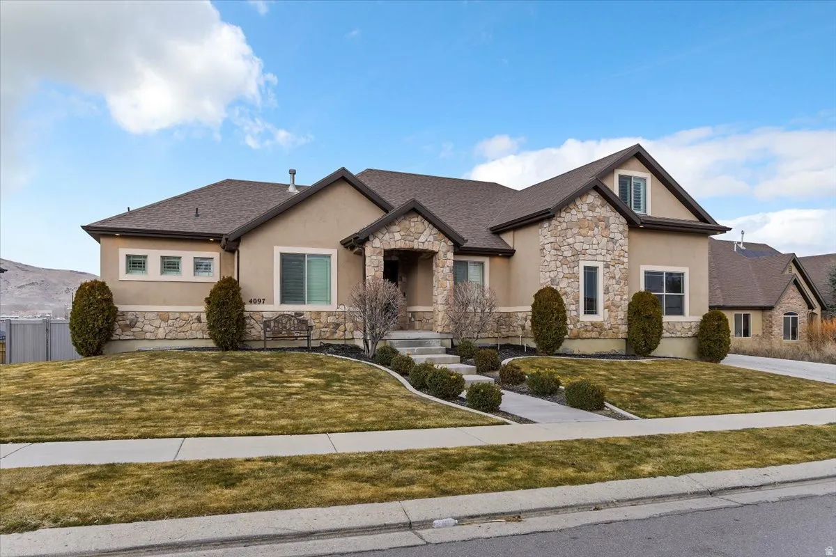 View of front of home with stone siding, stucco siding, and a front lawn