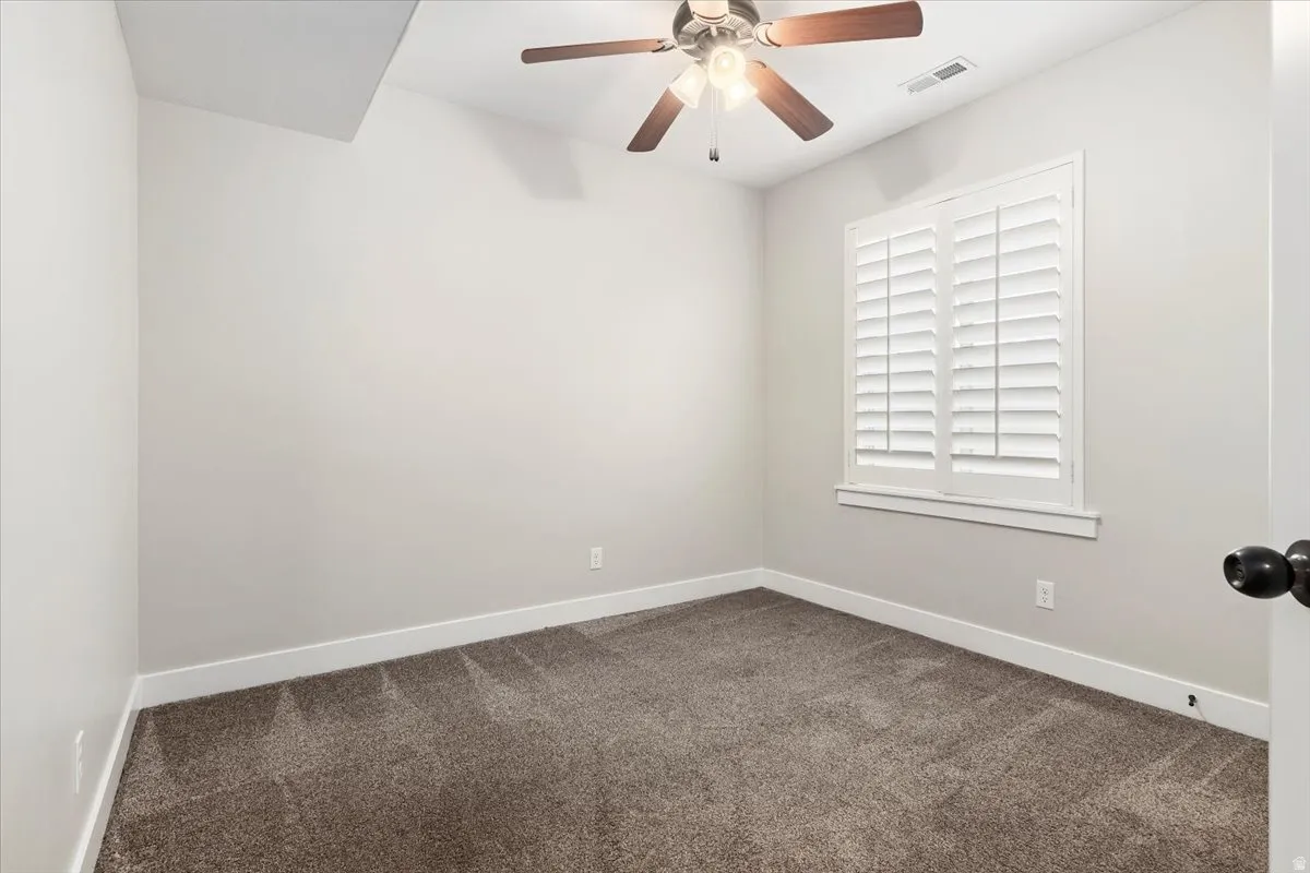Spare room featuring dark carpet and a ceiling fan