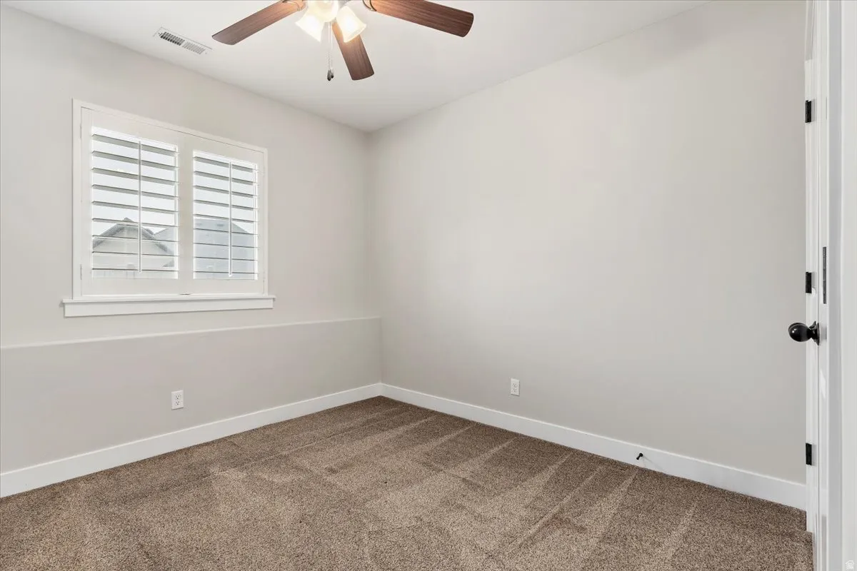 Carpeted spare room with baseboards and a ceiling fan