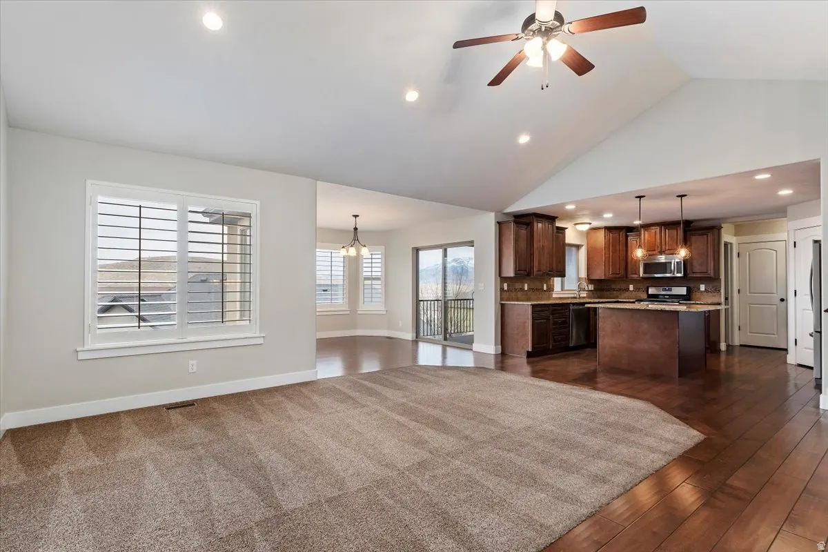 Kitchen with open floor plan, ceiling fan, light countertops, a kitchen island, and healthy amount of natural light