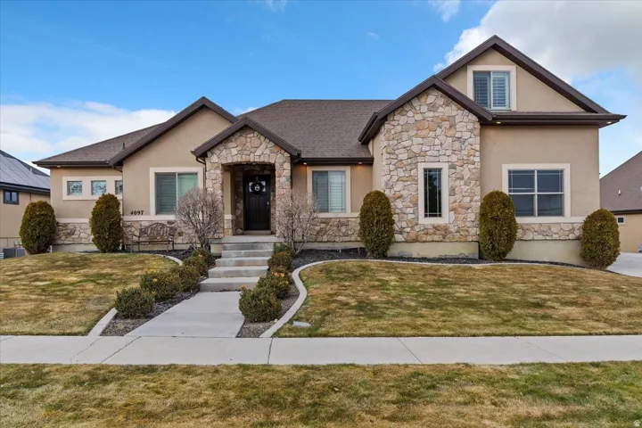 View of front of property featuring stone siding, a front lawn, and stucco siding