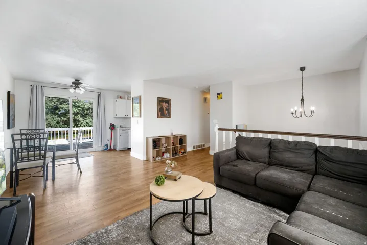 Living area featuring light wood-style floors, ceiling fan, and hanging lights