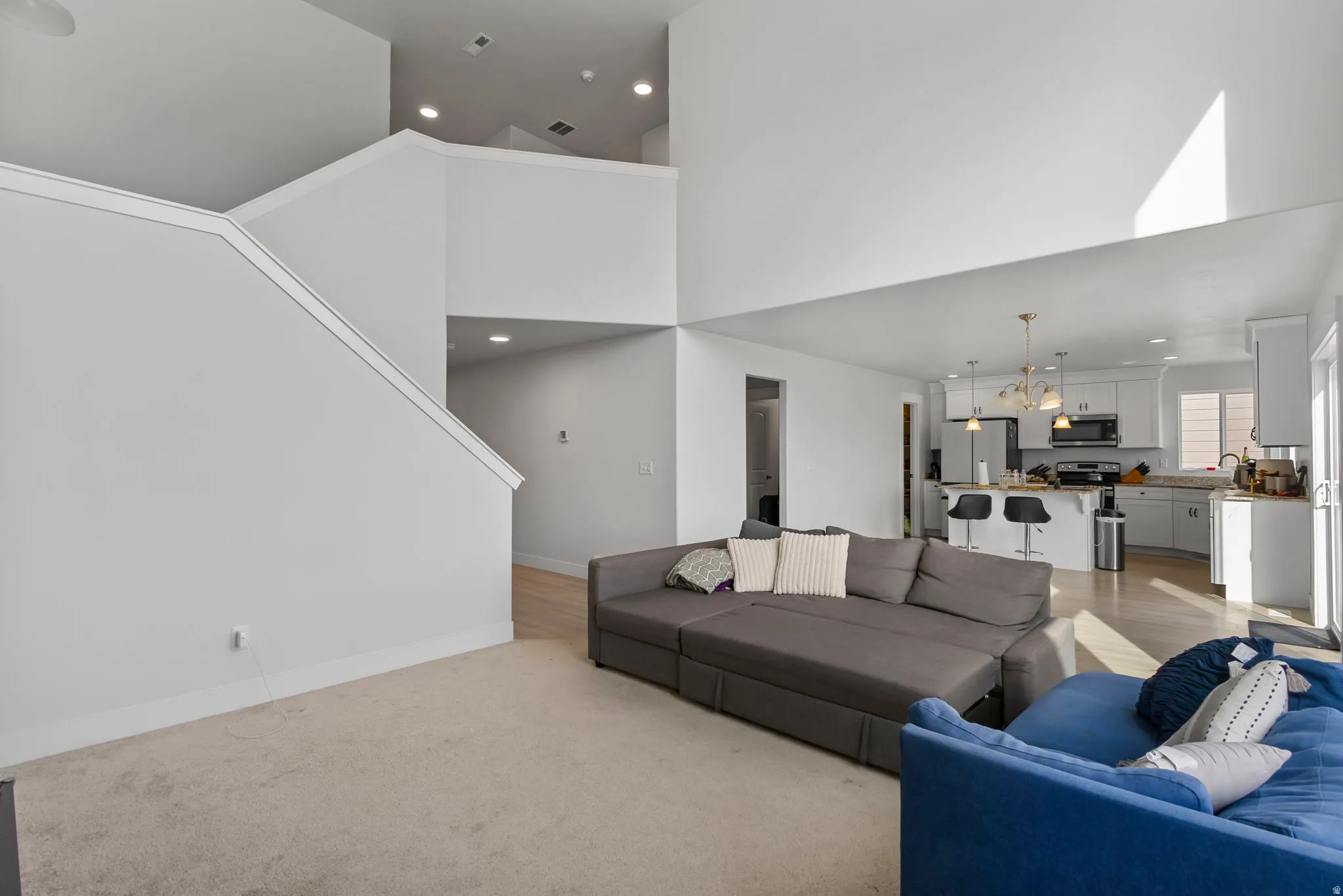 Living area with a high ceiling, light carpet, and a chandelier