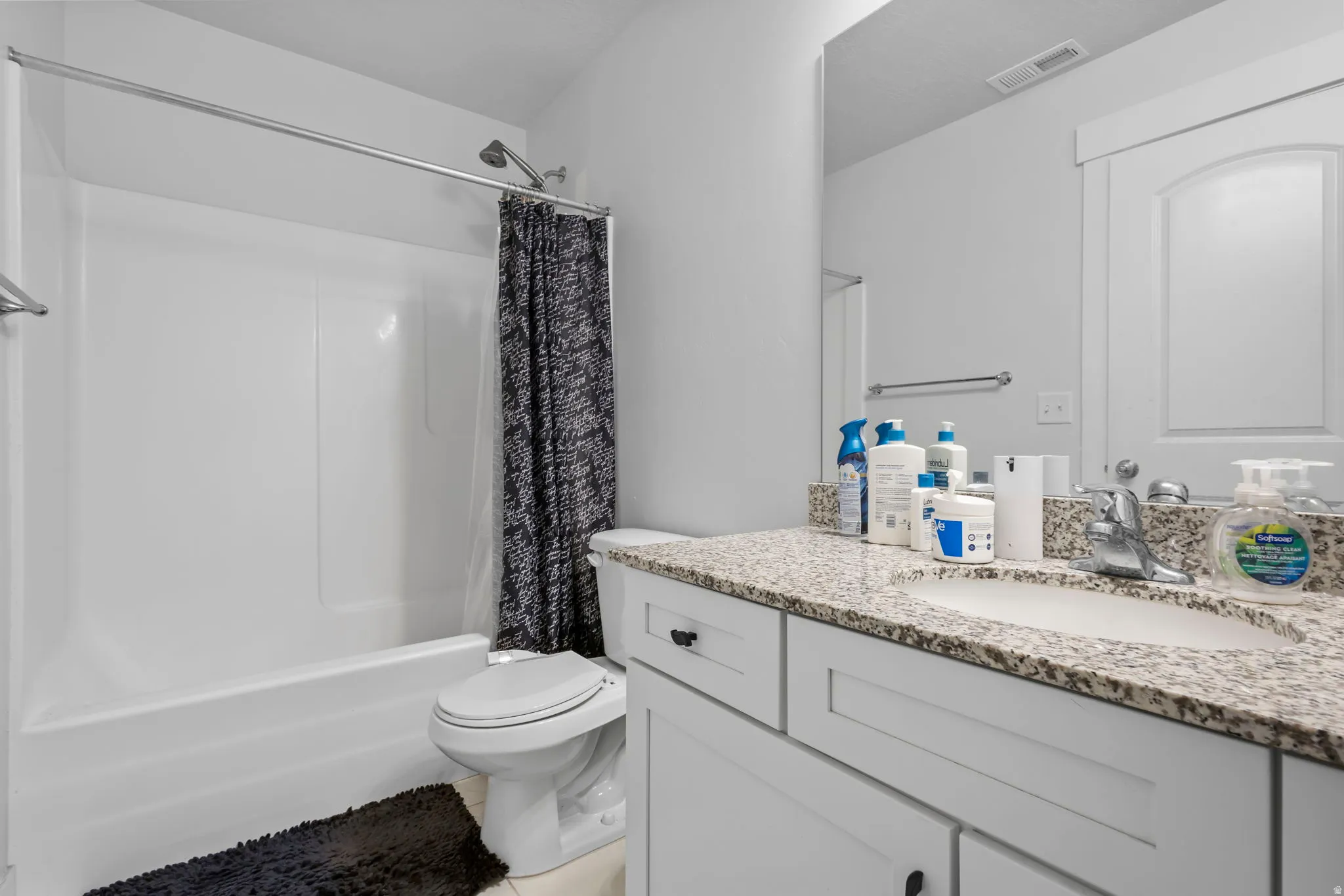 Full bath with vanity, shower / tub combo with curtain, and light tile patterned flooring