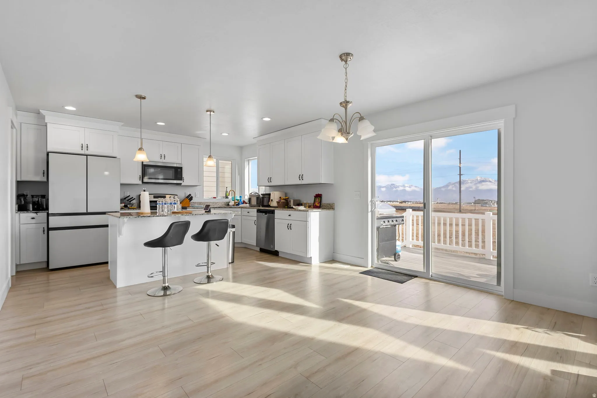 Kitchen with stainless steel appliances, a kitchen bar, white cabinets, a center island, and light wood-style flooring