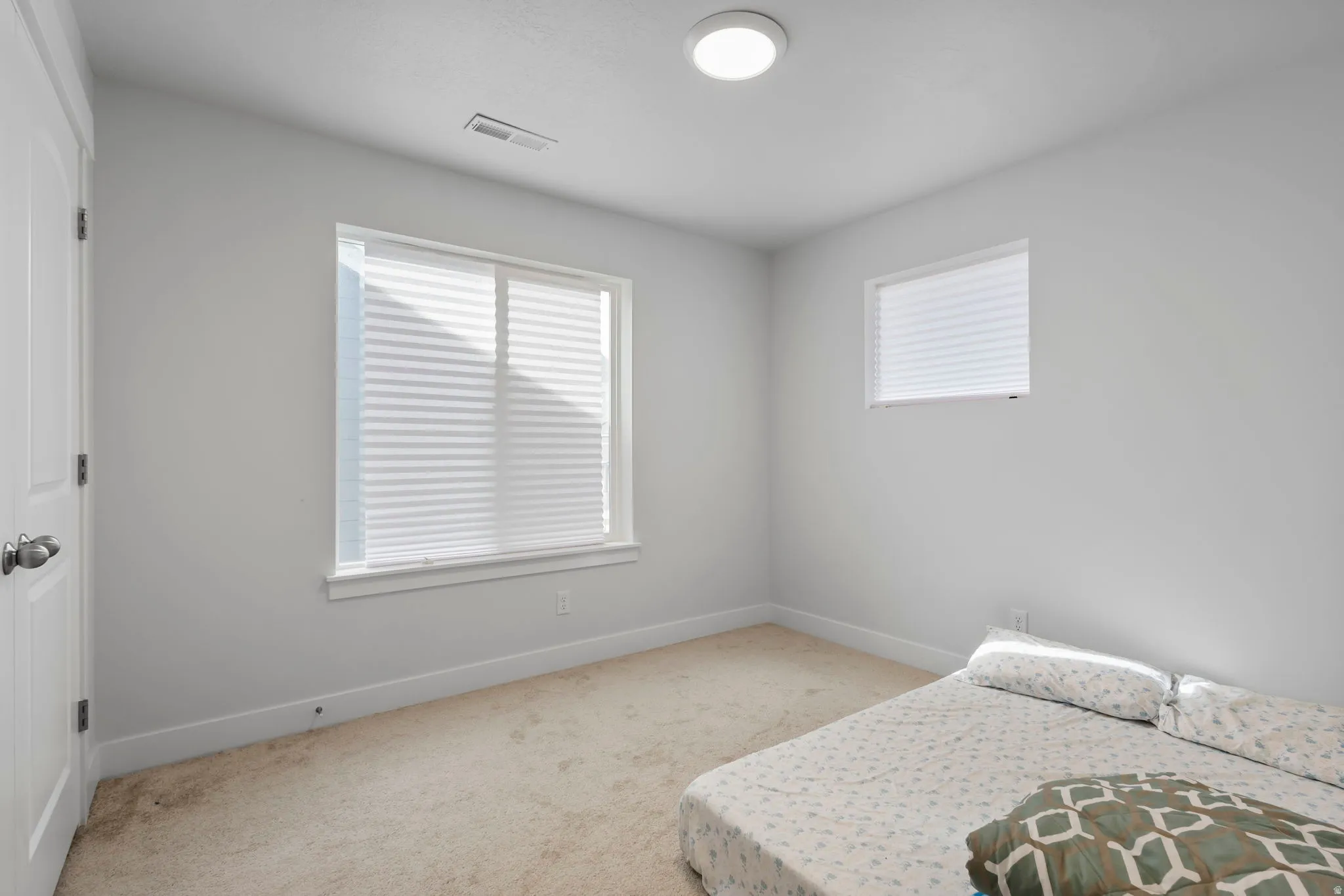 Bedroom featuring light carpet and multiple windows