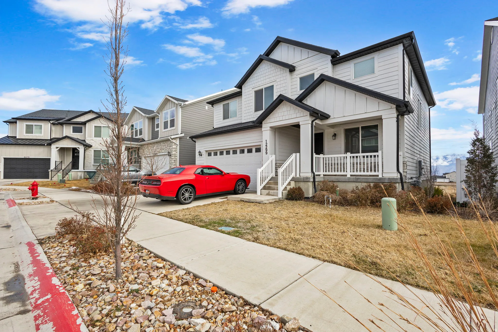 View of front of property featuring board and batten siding, covered porch, an attached garage, concrete driveway, and a residential view